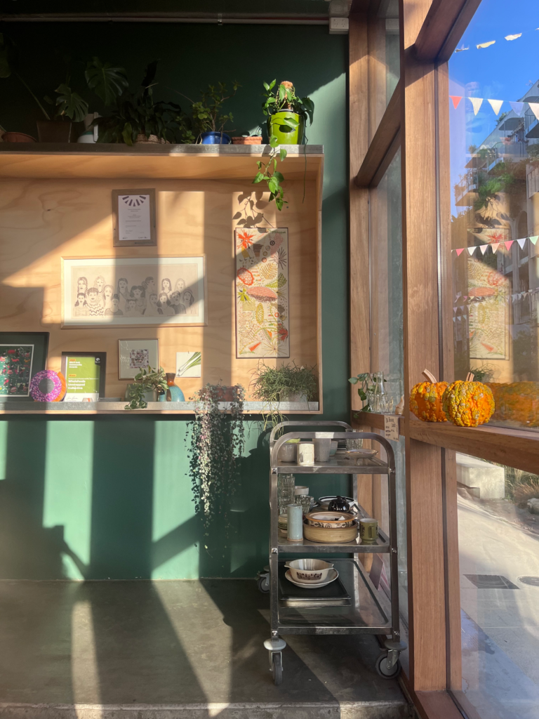 Sun-drenched entrance of Wholefoods Unwrapped Collective in Brunswick featuring local community art.