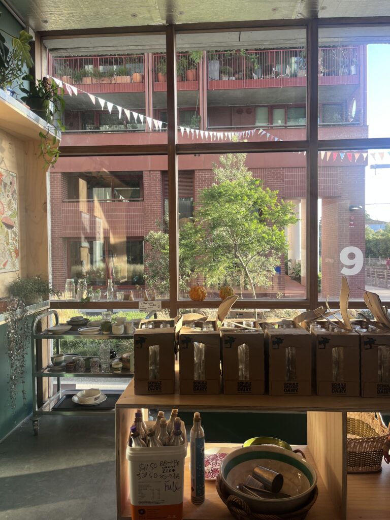 View of the Nightingale Village courtyard from Wholefoods Unwrapped Collective with Schulz returnable glass bottles in the foreground.